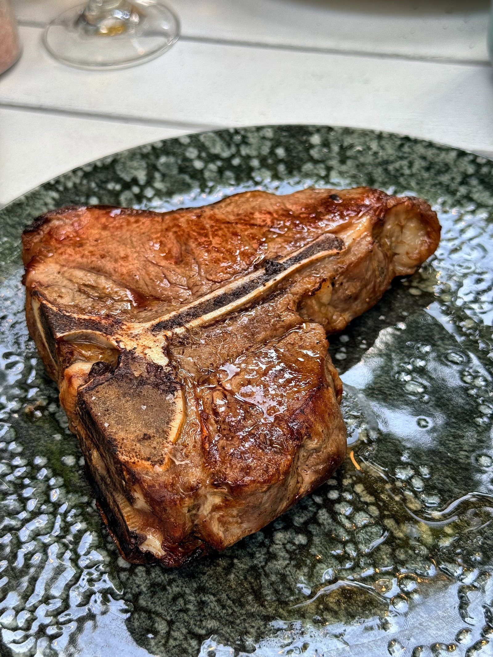 Bucată de carne la grătar, servită pe farfurie de ceramică închisă la culoare